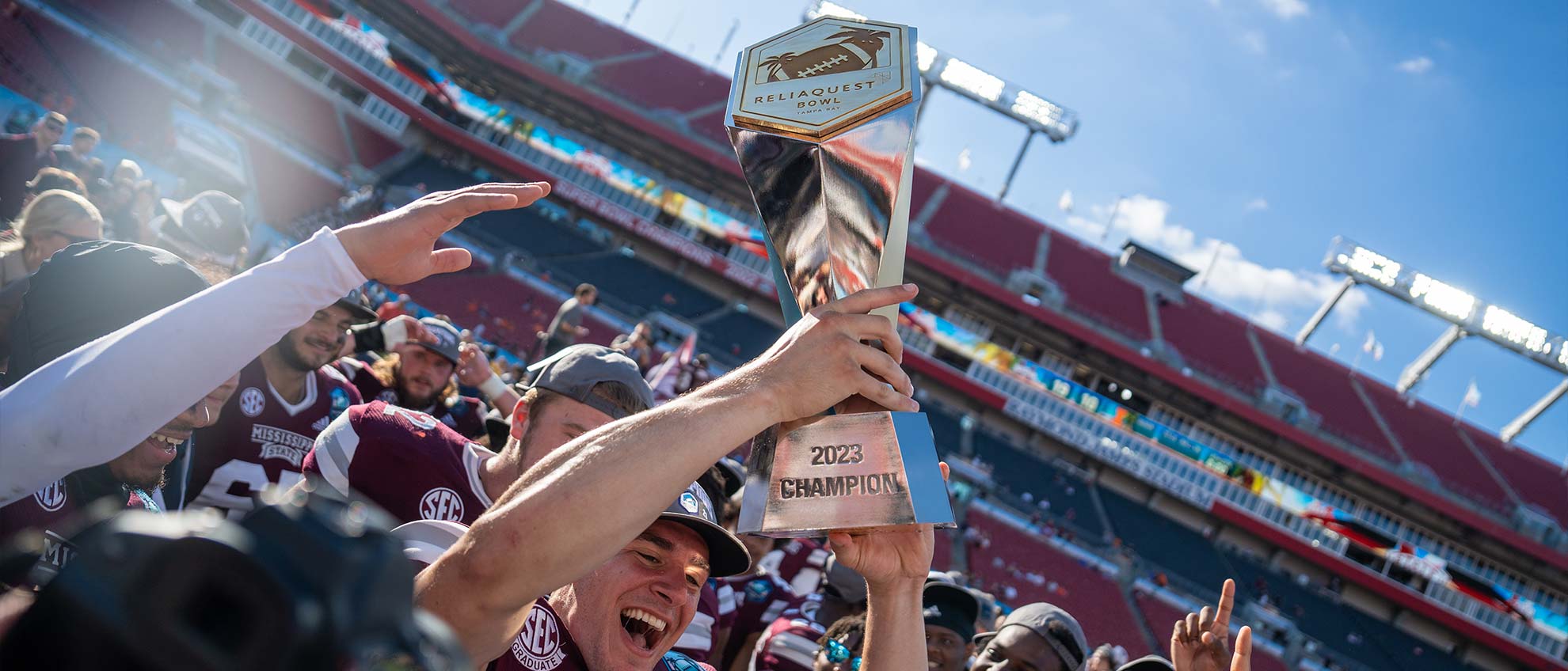 A Mississippi State player hoists the ReliaQuest Bowl trophy in celebration